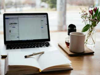 MacBook Pro near white open book by Nick Morrison courtesy of Unsplash.