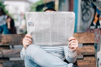 man sitting on bench reading newspaper by Roman Kraft courtesy of Unsplash.