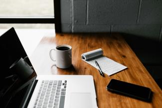 MacBook Pro, white ceramic mug,and black smartphone on table by Andrew Neel courtesy of Unsplash.