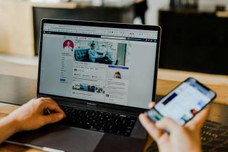 person using both laptop and smartphone by Austin Distel courtesy of Unsplash.