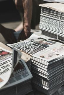 shallow focus photography of piles of newspapers by Thomas Charters courtesy of Unsplash.