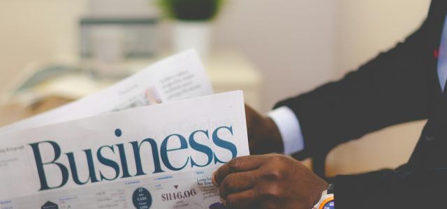 person wearing suit reading business newspaper by Adeolu Eletu courtesy of Unsplash.