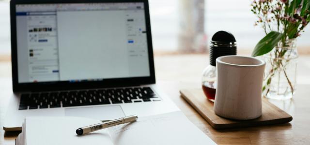 MacBook Pro near white open book by Nick Morrison courtesy of Unsplash.