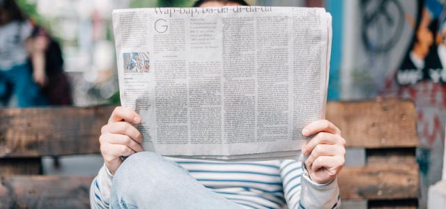 man sitting on bench reading newspaper by Roman Kraft courtesy of Unsplash.