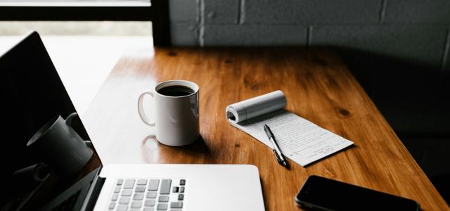 MacBook Pro, white ceramic mug,and black smartphone on table by Andrew Neel courtesy of Unsplash.