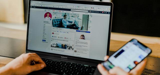 person using both laptop and smartphone by Austin Distel courtesy of Unsplash.