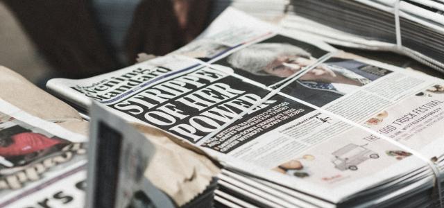 shallow focus photography of piles of newspapers by Thomas Charters courtesy of Unsplash.